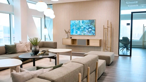 Corporate lounge with large windows, natural light and wooden details — Nordic office design promoting openness and collaboration.