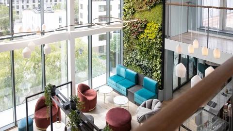 Hotel lounge area with green wall and large windows offering city view.