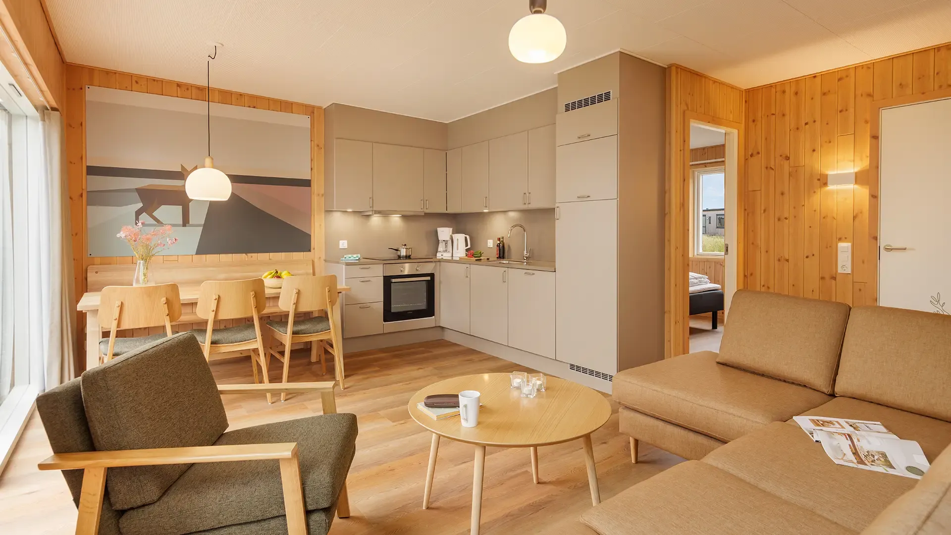 Open-plan living and kitchen area with integrated dining and contract furniture in a resort cottage at Nordborg Resort.