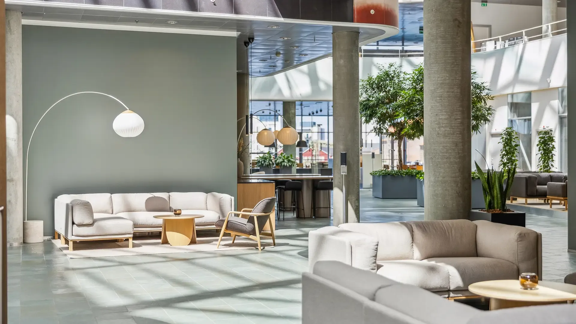 Office foyer with sofas and coffee tables surrounded by greenery, designed for employee wellbeing.
