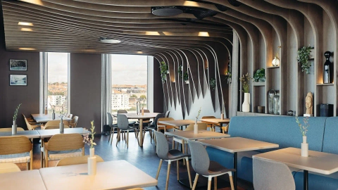 Dining area with custom-built furniture and architectural, acoustic ceiling, optimizing space and visual coherence in the restaurant.